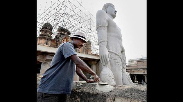 A worker plasters a wall next to the free-standing statue built around 983 A.D. The ceremony will see devotees carrying 1,008 specially prepared vessels. The statue will then be anointed with libations such as milk, sugarcane juice, saffron paste and water and sprinkled with sandalwood, turmeric, and vermilion powders. (PTI)