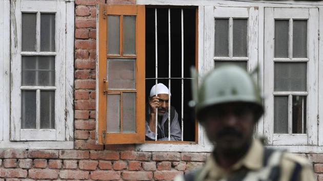 A Kashmiri man looks out from a window as a paramilitary soldier stands guard during a curfew in Srinagar after Wani’s death. (Waseem Andrabi / HT Photo) A Kashmiri man looks out from a window as a paramilitary soldier stands guard during a curfew in Srinagar after Wani’s death. (Waseem Andrabi / HT Photo)