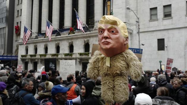 A man holds up an effigy of US President Donald Trump during a protest against the tax overhaul plan, in front of the New York Stock Exchange, December 19, 2017 (AP) A man holds up an effigy of US President Donald Trump during a protest against the tax overhaul plan, in front of the New York Stock Exchange, December 19, 2017 (AP)