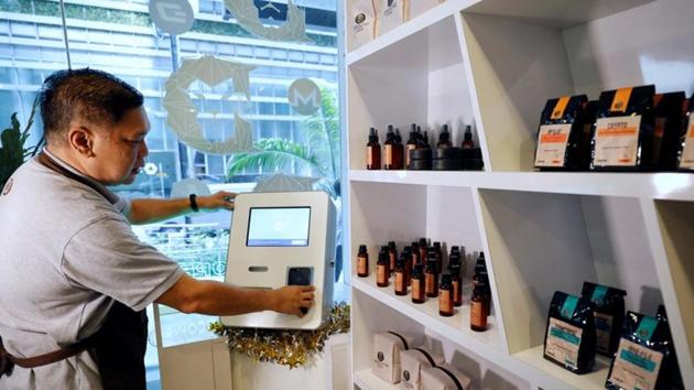 Ducatus franchise manager Philip Lim shows how a deposit is made at a Bitcoin ATM at the opening of their first cashless cafe that accepts cryptocurrencies such as Bitcoin in Singapore.(REUTERS)