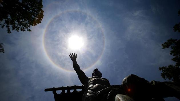 A statue seems to reach out to the sun encircled in a solar halo in Santiago, Chile on December 18, 2017. (Ivan Alvarado / REUTERS) A statue seems to reach out to the sun encircled in a solar halo in Santiago, Chile on December 18, 2017. (Ivan Alvarado / REUTERS)