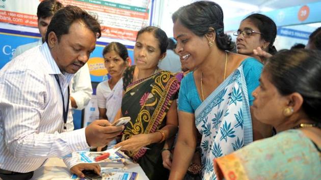 A bank employee (L) explains to visitors about account transactions from a mobile phone with Aadhaar or Unique Identification (UID) card in Hyderabad on January 18, 2017.(AFP File Photo)