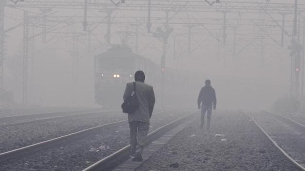 People walk along a railway line amid dense smog at Tilak Bridge railway station in New Delhi on Thursday. (Arvind Yadav / HT PHOTO)