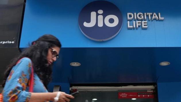 A woman checks her mobile phone as she walks past a mobile store of Reliance Industries' Jio telecoms unit, in Mumbai.(Reuters)