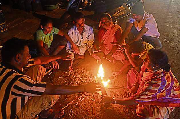 People sit around a campfire to keep themselves warm on a winter evening on Monday. (Pratham Gokhale/HT Photo) People sit around a campfire to keep themselves warm on a winter evening on Monday. (Pratham Gokhale/HT Photo)