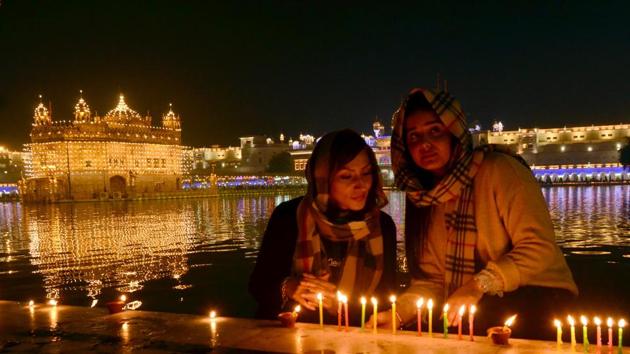 Devotees light candles as they pay respects at the illuminated Golden Temple on the occasion of birth anniversary of Guru Gobind Singh in Amritsar on Monday. (Sameer Sehgal/HT) Devotees light candles as they pay respects at the illuminated Golden Temple on the occasion of birth anniversary of Guru Gobind Singh in Amritsar on Monday. (Sameer Sehgal/HT)