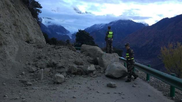 In this photo released by China's Xinhua news agency, rescuers look at a road blocked by fallen rocks in Tibet region on November 18, 2017. Experts said three artificial lakes created after the quake may pose threat to Assam and Arunachal Pradesh. (AP) In this photo released by China's Xinhua news agency, rescuers look at a road blocked by fallen rocks in Tibet region on November 18, 2017. Experts said three artificial lakes created after the quake may pose threat to Assam and Arunachal Pradesh. (AP)