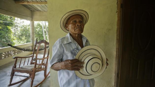 Pasion Gutierrez, 81, holds a finished pintao hat at his home in El Jaguito, Panama. The round painted hats of circular brim are light, handmade from five different plants and a dose of swamp mud, and still made on a household scale with various family members typically pitching in. (Arnulfo Franco / AP)