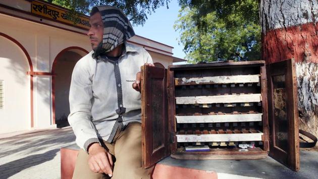 Mahendra Kumar of Palthana village is the designated ticket seller at the station. Kumar, who teaches at a local private school, operates under a tree with a small wooden chest holding tickets in slots to different destinations on the route. (Himanshu Vyas / HT Photo)