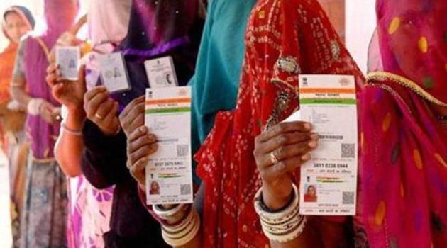 Women show their Aadhaar cards while standing in a queue. Jail authorities in Kerala plan to keep the Aadhaar number of prisoners in their data bank to keep a tab on them. (PTI / Representative Photo) Women show their Aadhaar cards while standing in a queue. Jail authorities in Kerala plan to keep the Aadhaar number of prisoners in their data bank to keep a tab on them. (PTI / Representative Photo)