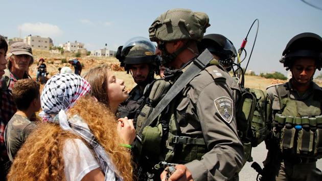 Ahed Tamimi (C) protesting in solidarity with Palestinian prisoners on hunger strike in Israeli jails on May 12, 2017. Palestinian reactions while troubled by the soldiers’ poise and the humane image it conveys of the Israeli security forces have also been inspirational: “The people of Palestine and all free peoples in the world salute you, Ahed,” wrote Kathem Nasser on Rai Al-Youm, a news site based in London. “We kiss your hand in reverence.” (Abbas Momani / AFP File) Ahed Tamimi (C) protesting in solidarity with Palestinian prisoners on hunger strike in Israeli jails on May 12, 2017. Palestinian reactions while troubled by the soldiers’ poise and the humane image it conveys of the Israeli security forces have also been inspirational: “The people of Palestine and all free peoples in the world salute you, Ahed,” wrote Kathem Nasser on Rai Al-Youm, a news site based in London. “We kiss your hand in reverence.” (Abbas Momani / AFP File)