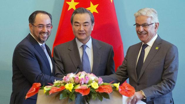 (From left) Afghanistan foreign minister Salahuddin Rabbani, Chinese FM Wang Yi and Pakistani FM Khawaja Asif hold hands to pose for a photo after a press conference for the first China-Afghanistan-Pakistan foreign ministers’ dialogue held in Beijing on Tuesday.(AP)