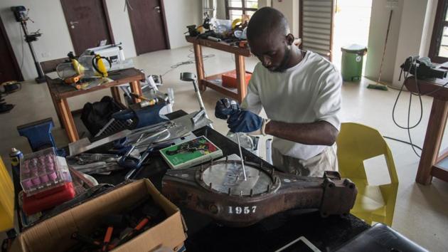 Joseph Awuah-Darko works on a clock, the pieces of which were found at Agbogloshie dumpsite, at his workshop in Ashesi University. When he first saw the piles of circuit boards, wires and plastics, he decided to use his artistic talent as a force for change.The students straddle between two worlds --a life on the lush campus of a private university in a forested area and a life among some of Ghana’s poorest . (Cristina Aldehuela / AFP) 