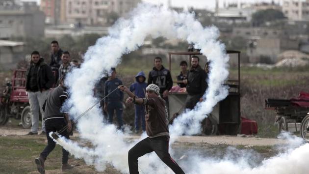 A Palestinian protester slings a tear gas canister towards Israeli soldiers during clashes on the Israeli border with Gaza on December 22, 2017. (Khalil Hamra / AP) A Palestinian protester slings a tear gas canister towards Israeli soldiers during clashes on the Israeli border with Gaza on December 22, 2017. (Khalil Hamra / AP)