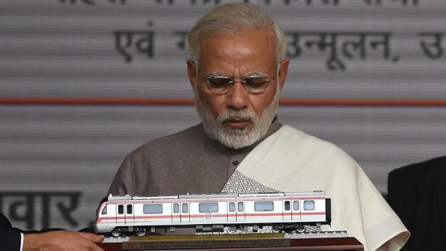 PM Narendra Modi looks on a model of Metro train during the inauguration of a12.64km Delhi Metro Magenta Line, connecting the Botanical Garden in Noida to Kalkaji Mandir in South Delhi in Noida on December 25, 2017. (Prakash Singh / AFP)