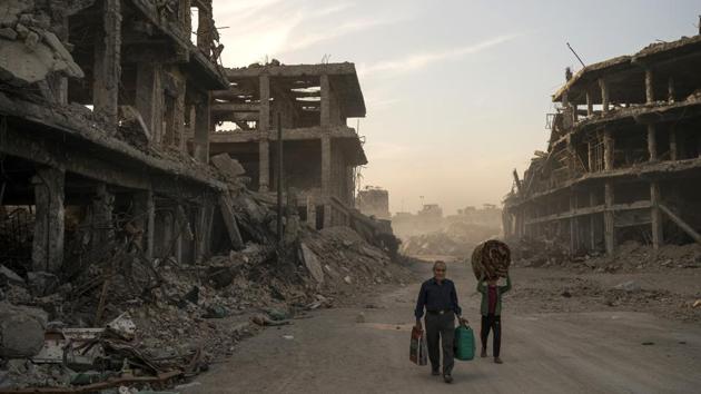 Haider (L), and Abdullah carry belongings from their damaged house before returning to the Mosul’s Old City. Three years of war devastated much of northern and western Iraq, Baghdad estimates $100 billion is needed nationwide to rebuild. Local leaders in Mosul, the biggest city held by IS, say that amount is needed to rehabilitate their city alone. So far no one is offering to foot the bill. (Felipe Dana / AP) Haider (L), and Abdullah carry belongings from their damaged house before returning to the Mosul’s Old City. Three years of war devastated much of northern and western Iraq, Baghdad estimates $100 billion is needed nationwide to rebuild. Local leaders in Mosul, the biggest city held by IS, say that amount is needed to rehabilitate their city alone. So far no one is offering to foot the bill. (Felipe Dana / AP)