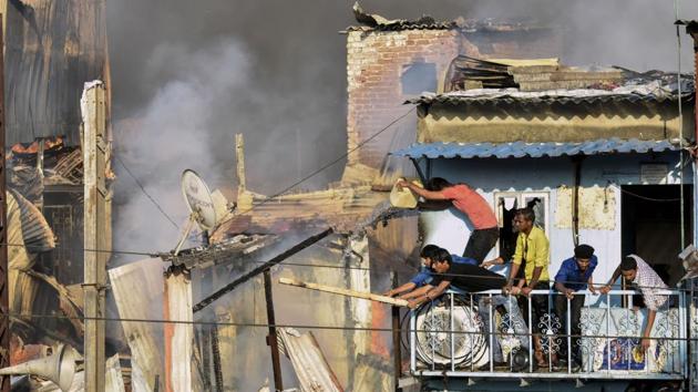 Local resident extinguish a fire that broke out at Garib Nagar in Bandra in Mumbai. The fire broke out when BMC officials were conducting an encroachment removal drive along Tansa pipeline, following a Bombay High Court order. (Kunal Patil / HT Photo) 