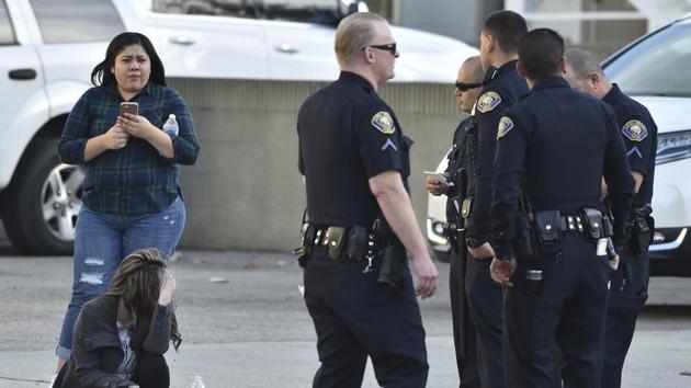 Employees from a nearby business sit with police after the Long Beach police responded to an active shooter in Long Beach, California. (AP Photo)