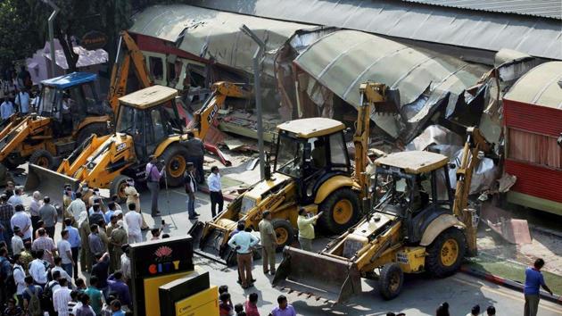 Onlookers gather around as the BMC bulldozers take down illegally constructed eateries in the Kamala Mills compound following the fire incident, in Mumbai on Saturday. (PTI) Onlookers gather around as the BMC bulldozers take down illegally constructed eateries in the Kamala Mills compound following the fire incident, in Mumbai on Saturday. (PTI)