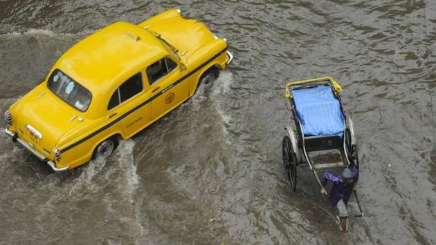 Kolkata’s famous yellow taxi and the infamous hand rickshaw cross paths on a rainy October day.  (Samir Jana / HT Photo) 