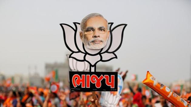 A supporter holds up a cut-out of a lotus, the election symbol of the ruling Bharatiya Janata party (BJP), with an image of Prime Minister Narendra Modi during a campaign meeting addressed by Modi ahead of Gujarat state assembly election in Kalol on the outskirts of Ahmedabad on December 8, 2017. (REUTERS)