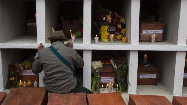 An Ixil Maya man prays next to the niches in Santa Avelina cemetary. Since the exhumations began, experts have identified 108 of the victims through DNA testing or through personal objects recognized by family members. The return of the bodies has given relatives a place to bring flowers and light candles as per tradition. (AP)