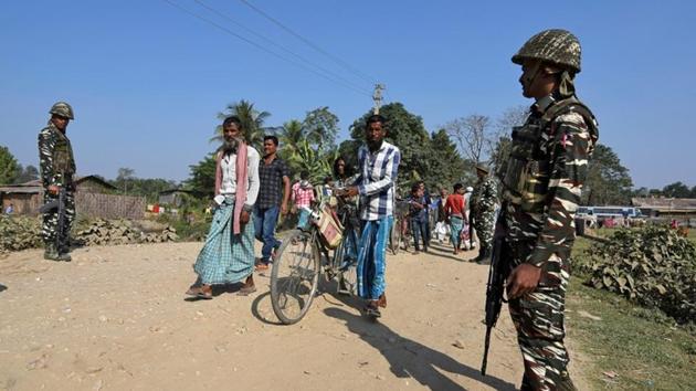 Villagers walk past Central Reserve Police Force (CRPF) personnel patrolling a road ahead of the publication of the first draft of the National Register of Citizens (NRC) in the Juria village of Nagaon district in Assam, on December 28, 2017.(Reuters) Villagers walk past Central Reserve Police Force (CRPF) personnel patrolling a road ahead of the publication of the first draft of the National Register of Citizens (NRC) in the Juria village of Nagaon district in Assam, on December 28, 2017.(Reuters)