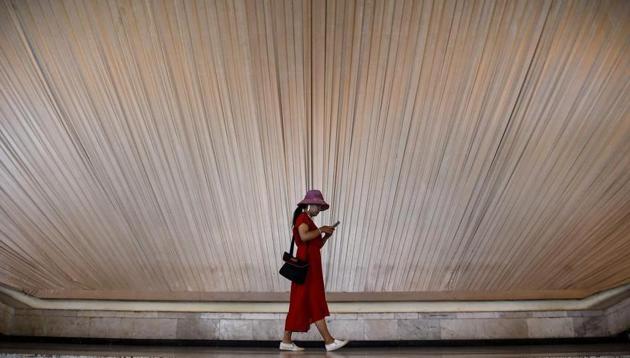 A woman looks at her phone as she walks inside an exhibition centre in Shanghai.(AFP File Photo)