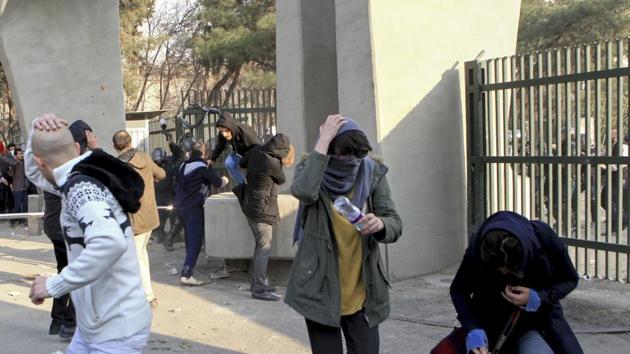 In this photo taken on December 30, 2017, university students run away from stones thrown by police during an anti-government protest inside Tehran University (AP) In this photo taken on December 30, 2017, university students run away from stones thrown by police during an anti-government protest inside Tehran University (AP)