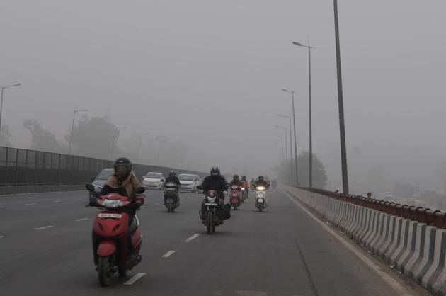 With streetlights on many stretches switched off in the morning, commuters had a tough time navigating the streets through the dense fog.(Parveen Kumar/HT PHOTO)