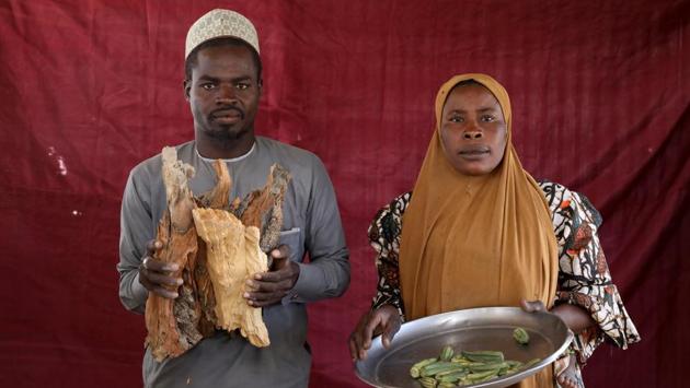 Isa Zakariya Audu (L), holds pieces of firewood whilst Kakaye Ahmadu Maikifi holds up a plate of okra. More than 670,000 live in camps in Nigeria’s northeast, where cash is hard to come by, opportunities for work are rare and the food and aid they receive is often not what they want. (Afolabi Sotunde / REUTERS) Isa Zakariya Audu (L), holds pieces of firewood whilst Kakaye Ahmadu Maikifi holds up a plate of okra. More than 670,000 live in camps in Nigeria’s northeast, where cash is hard to come by, opportunities for work are rare and the food and aid they receive is often not what they want. (Afolabi Sotunde / REUTERS)