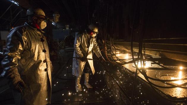 Workers clean the candles, at Sidor’s Palanquilla plant. Only two of the four smelting ovens that make steel bars are functioning at the plant, and workers who once operated around the clock put in just one shift a day now, officials said. (Rodrigo Abd / AP) 