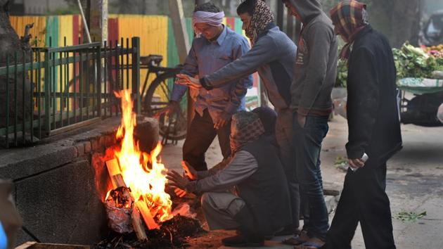 People warm themselves next to a bonfire at Mayur Vihar in New Delhi.(Sushil Kumar/HT PHOTO)