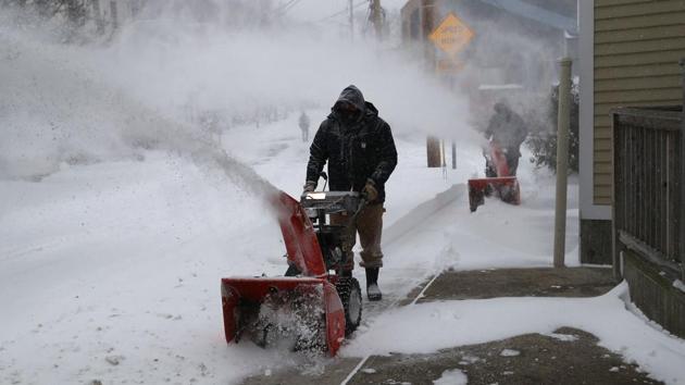 People remove snow from the sidewalks in New Haven, Connecticut. Officials feared fast-dropping temperatures after the storm passed would turn snow on roadways to ice. Ahead of that threat, snow plows and salt trucks were dispatched along streets and highways. In Boston, Mayor Marty Walsh said schools would remain closed on Friday. (John Moore / Getty Images / AFP)