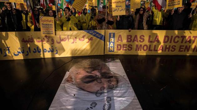 Protesters hold placards reading “Support Iranians risen up against the religious dictatorship” as they stand behind a portrait of Iranian President Hassan Rouhani with shoe marks over it during a demonstration on January 03, 2018 in Paris, France. (Lionel Bona Venture / AFP) Protesters hold placards reading “Support Iranians risen up against the religious dictatorship” as they stand behind a portrait of Iranian President Hassan Rouhani with shoe marks over it during a demonstration on January 03, 2018 in Paris, France. (Lionel Bona Venture / AFP)