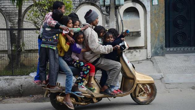 Indian children ride on a motorbike driven by a man along a street in Jalandhar. (Shammi Mehra / AFP) Indian children ride on a motorbike driven by a man along a street in Jalandhar. (Shammi Mehra / AFP)
