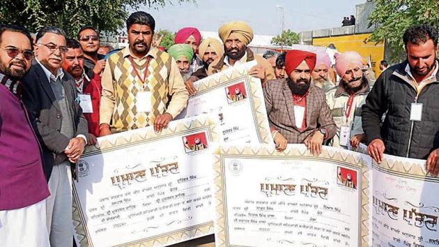 Farmers displaying their cheques received under the crop loan-waiver scheme in Mansa on Sunday.(HT Photo)