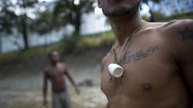 A medicine bottle hangs from a scavenger’s neck, where he keeps the small pieces of gold and other finds from the water. The day’s haul -- a keychain and an old coin -- is taken to the Bolivar Plaza, where vendors offer cash for gold. (Ariana Cubillos / AP) A medicine bottle hangs from a scavenger’s neck, where he keeps the small pieces of gold and other finds from the water. The day’s haul -- a keychain and an old coin -- is taken to the Bolivar Plaza, where vendors offer cash for gold. (Ariana Cubillos / AP)