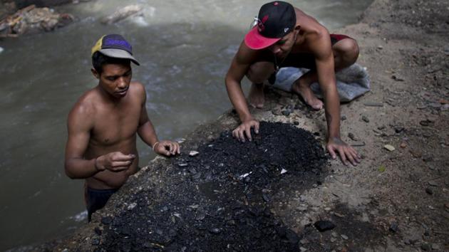 Images of Venezuelans eating from garbage piles have come to symbolize the deepening economic crisis. Less visible are the young men who comb these waters to feed families. At times playing, shirtless and laughing in groups, the sun reflects off their backs as they scoop up rocks and toss them aside in waters that are also drains for sewage and industrial waste. (Ariana Cubillos / AP) Images of Venezuelans eating from garbage piles have come to symbolize the deepening economic crisis. Less visible are the young men who comb these waters to feed families. At times playing, shirtless and laughing in groups, the sun reflects off their backs as they scoop up rocks and toss them aside in waters that are also drains for sewage and industrial waste. (Ariana Cubillos / AP)