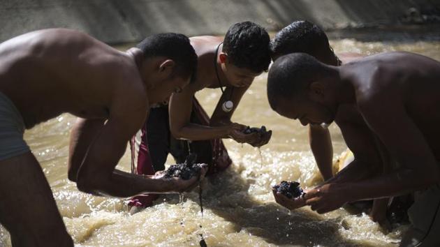 Alongside other scavengers, Angel Villanueva (R) looks for pieces of gold and valuables in the debris he scooped up from the riverbed. This work requires constant awareness of the fact that the mountains surrounding Caracas could burst at any time, leaving minutes to get out — or be washed away to one’s death. (Ariana Cubillos / AP) Alongside other scavengers, Angel Villanueva (R) looks for pieces of gold and valuables in the debris he scooped up from the riverbed. This work requires constant awareness of the fact that the mountains surrounding Caracas could burst at any time, leaving minutes to get out — or be washed away to one’s death. (Ariana Cubillos / AP)