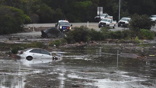 An abadoned car floats in flooded waters and debris on the freeway. Some areas of Santa Barbara County early on Tuesday were pounded with more than a half-inch of rain in five minutes, a rate that far exceeds the normal flash flood threshold, officials said. (Mike Eliason / Santa Barbara News-Press / REUTERS) 