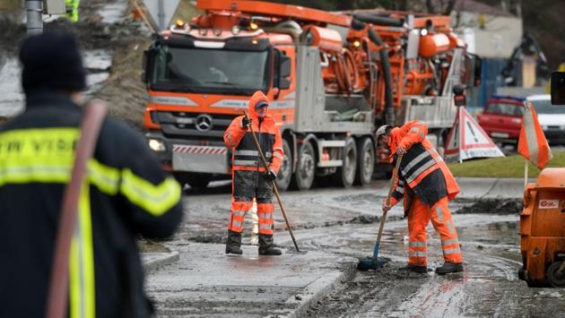 Workers remove mud and water after  the mudslide. For residents and emergency workers, still weighing the devastation of the fires, a day of grim rituals resumed: road closings, evacuations, downed power lines, heroic rescues and a search for the dead. (Fabrice Coffrini / AFP) 