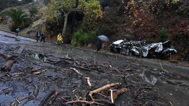 A firefighter (in yellow) instructs journalists to retreat to safer ground after a rain-driven mudslide destroyed two cars and damaged property in a neighborhood under mandatory evacuation in Burbank. (Robyn Beck / AFP) 