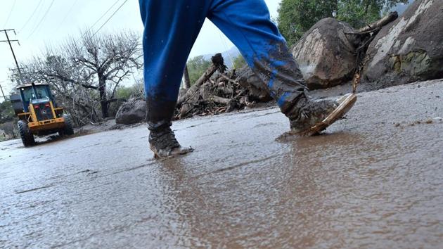 A man walks in front of a bulldozer clearing mud after boulders from surrounding hillsides came crashing down in Carpinteria, California on January 9, 2018. (AFP Photo) A man walks in front of a bulldozer clearing mud after boulders from surrounding hillsides came crashing down in Carpinteria, California on January 9, 2018. (AFP Photo)