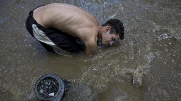 David Garcia, 19, keeps his head barely above water raking the bottom of the Guaire River in search of valuables to sell in Caracas. Still in his first week working in the toxic, drain fed waters he said that his family was unaware this was how he was trying to put food on the table. He is one among many in crisis-hit Venezuela driven to scavenging in this polluted river. (Ariana Cubillos / AP) David Garcia, 19, keeps his head barely above water raking the bottom of the Guaire River in search of valuables to sell in Caracas. Still in his first week working in the toxic, drain fed waters he said that his family was unaware this was how he was trying to put food on the table. He is one among many in crisis-hit Venezuela driven to scavenging in this polluted river. (Ariana Cubillos / AP)