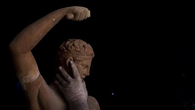 Haralambos Goumas feels the surface of a statue of Hermes. “It’s very hard, physically demanding work,” he said. “It’s not so easy to breathe in the smoke from the furnace, or lift these very heavy statues — some weigh 100 kilograms (220 pounds) and the moulds can reach 300 kilograms.” (Petros Giannakouris / AP)