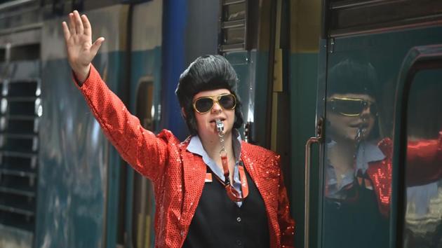 A train conductor dressed as Elvis signals for the train to leave Central station to take people to the Parkes Elvis Festival. Even on-board, Elvis tribute artists entertained passengers during the trip over mountains and through wheat fields and grazing pastures. (Peter Parks / AFP) A train conductor dressed as Elvis signals for the train to leave Central station to take people to the Parkes Elvis Festival. Even on-board, Elvis tribute artists entertained passengers during the trip over mountains and through wheat fields and grazing pastures. (Peter Parks / AFP)