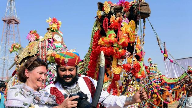 A tourist shows a picture to a camel owner during the inaugural ceremony of International Camel Festival in Bikaner. (PTI)