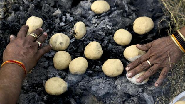 People make Litti for their evening meal before leaving the transit camp to Gangasagar, in Kolkata. Thousands of Hindu pilgrims are expected to take the annual holy dip at Gangasagar, where the Ganges River reaches the Bay of Bengal, on the auspicious Makar Sankranti festival day that falls on January 14. (Bikas Das / AP)