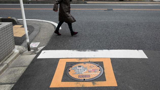A woman walks past a manhole cover bearing a firefighter in Kawaguchi. The cards are numbered in chronologically and come with the manhole’s GPS location. When a real cover does become available, demand is brisk. The city of Maebashi held a highly competitive lottery in October offering 10 used manhole covers -- 40 kilogrammes of iron -- at 3,000 yen ($28) with more than 190 bids for each cover. (Behrouz Mehri / AFP) A woman walks past a manhole cover bearing a firefighter in Kawaguchi. The cards are numbered in chronologically and come with the manhole’s GPS location. When a real cover does become available, demand is brisk. The city of Maebashi held a highly competitive lottery in October offering 10 used manhole covers -- 40 kilogrammes of iron -- at 3,000 yen ($28) with more than 190 bids for each cover. (Behrouz Mehri / AFP)